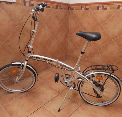 Manillar de la rueda delantera y cesta de una bicicleta femenina cerca de  una puerta de metal marrón