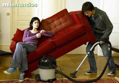 Hombre joven limpieza de sofá con aspiradora en dejar habitación en casa
