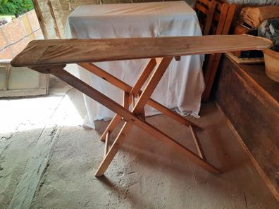 Plancha para planchar en una pequeña tabla de planchar de mesa en una  acogedora sala de estar, apartamentos pequeños