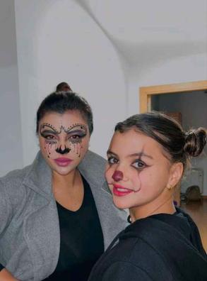 Una chica con un disfraz de animadora con maquillaje de esqueleto de media  cara y una chica con maquillaje de calabaza